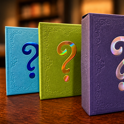 Three embossed mystery boxes with large question marks on the front, standing on a wooden table with a blurred library or bookstore background. The boxes are blue, green, and purple, with iridescent question marks.